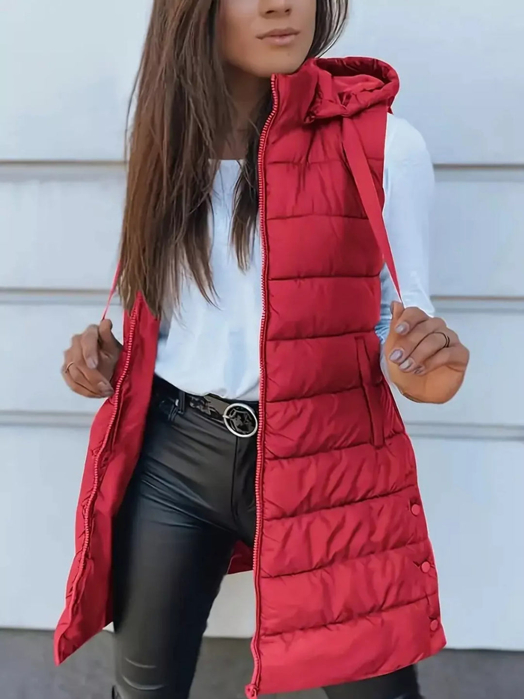 Red longline hooded puffer vest worn open with black pants