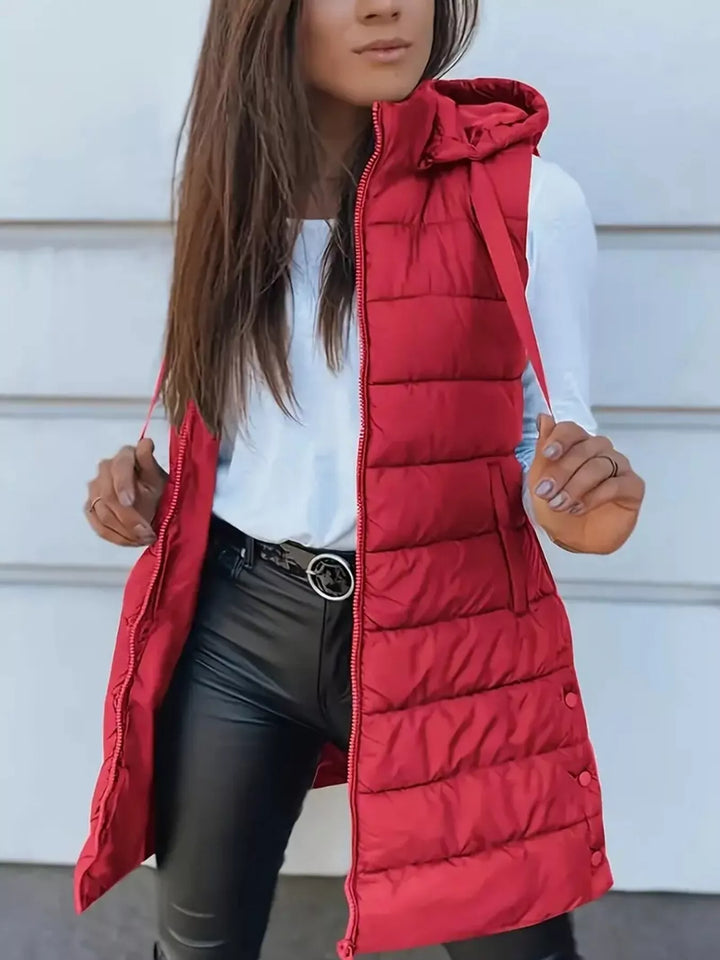 Red longline hooded puffer vest worn open with black pants