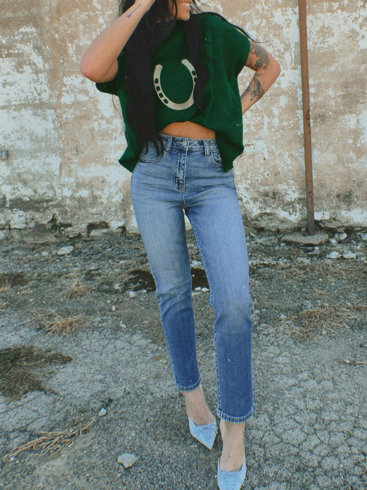 Dark green cropped horseshoe sweater styled with blue jeans and light blue heels