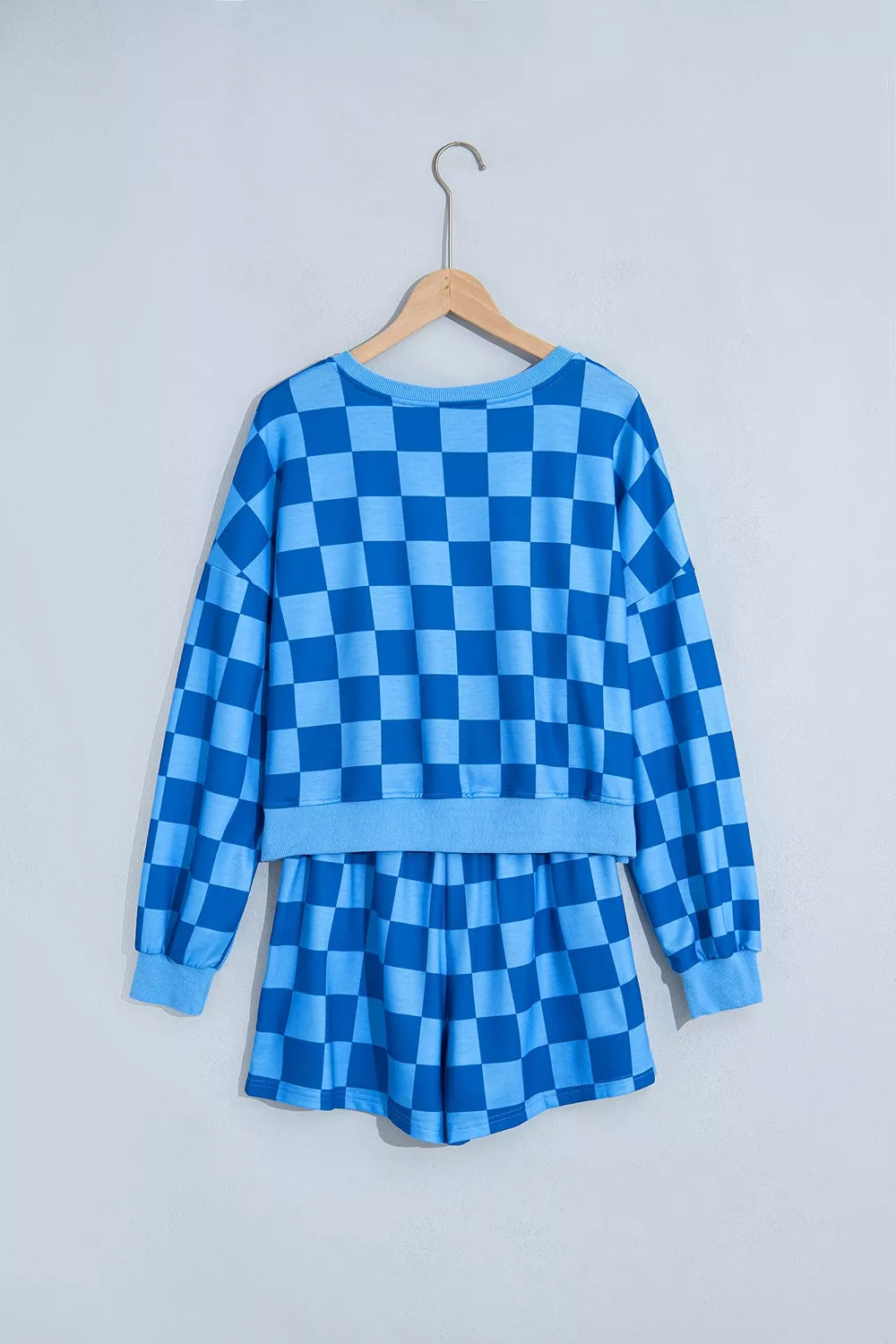 Blue checkerboard shorts set on a hanger, back view of the cropped top