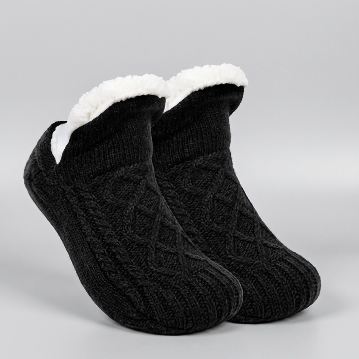 Pair of black cable knit slipper socks with folded fleece cuff