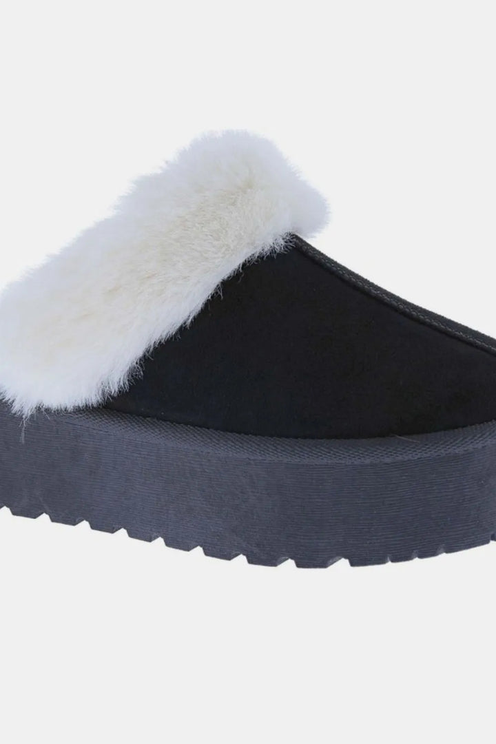 Close-up of black slipper with fluffy white trim and platform sole
