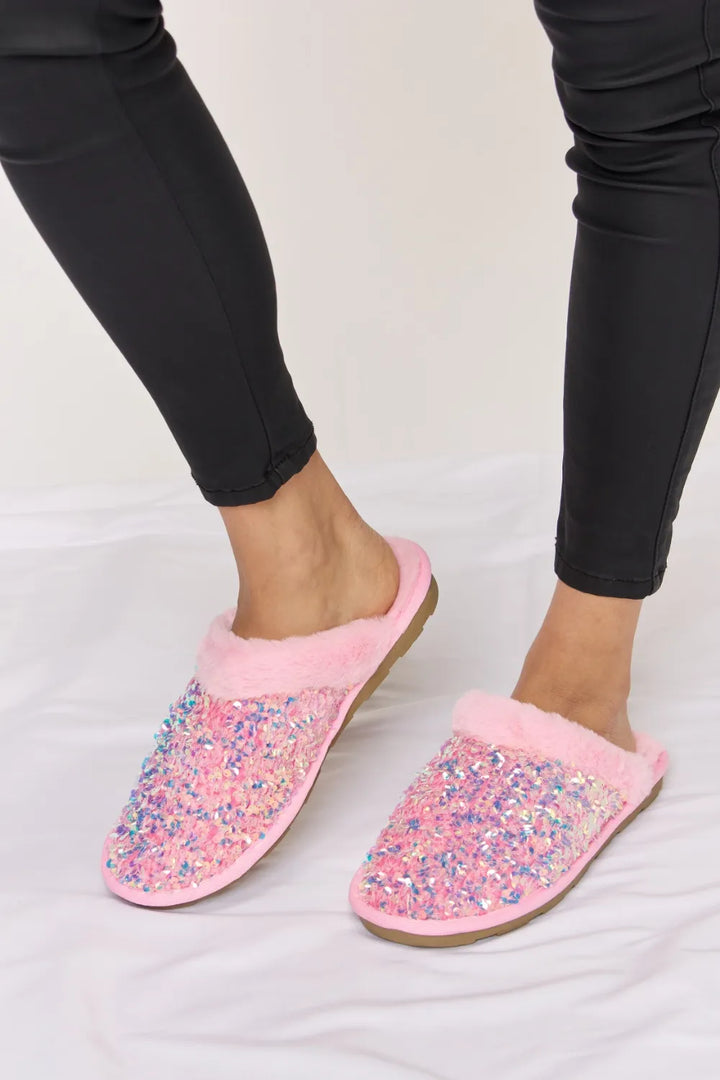 Pink slip on slippers with sequins, one foot lifted to show the sole edge