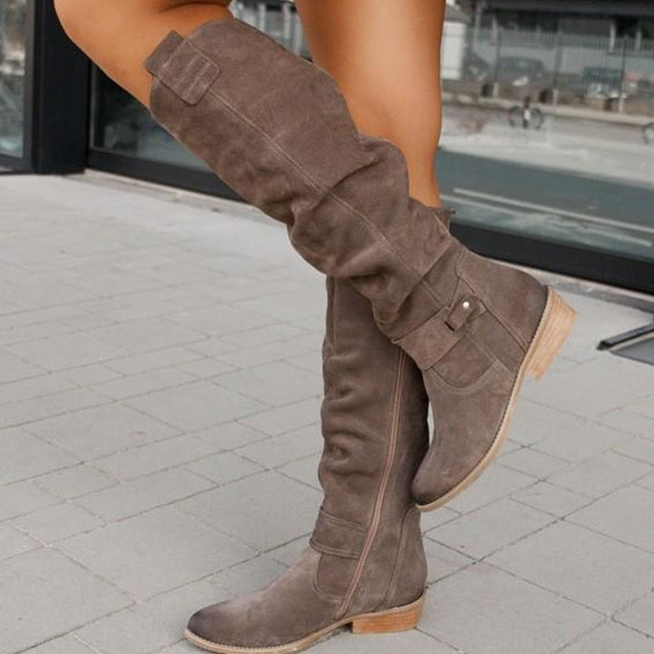 Grey knee high boot from the side with inner zip and stacked heel