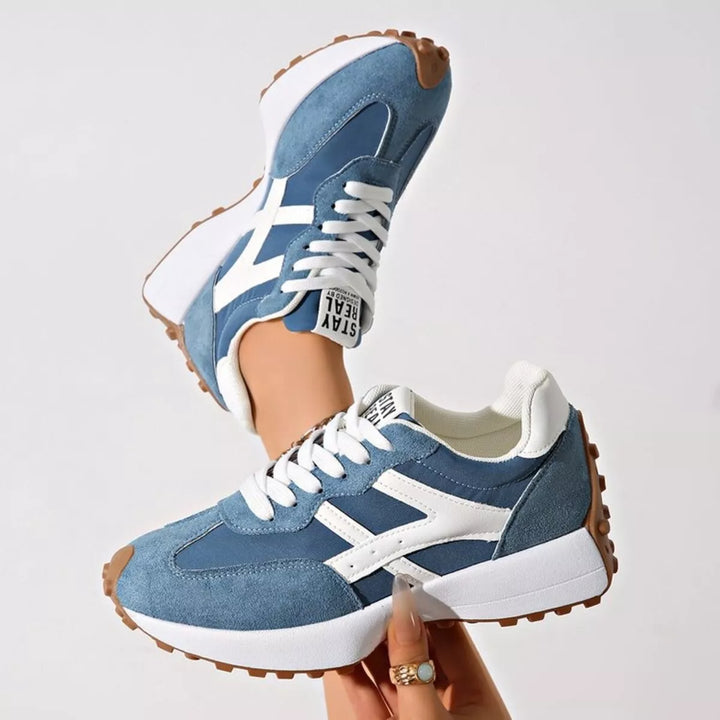 Denim blue lace up sneakers with mesh panels, side view held in hand