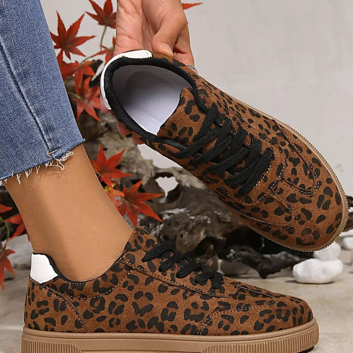 Leopard print sneaker held up to show the lace up top and side profile