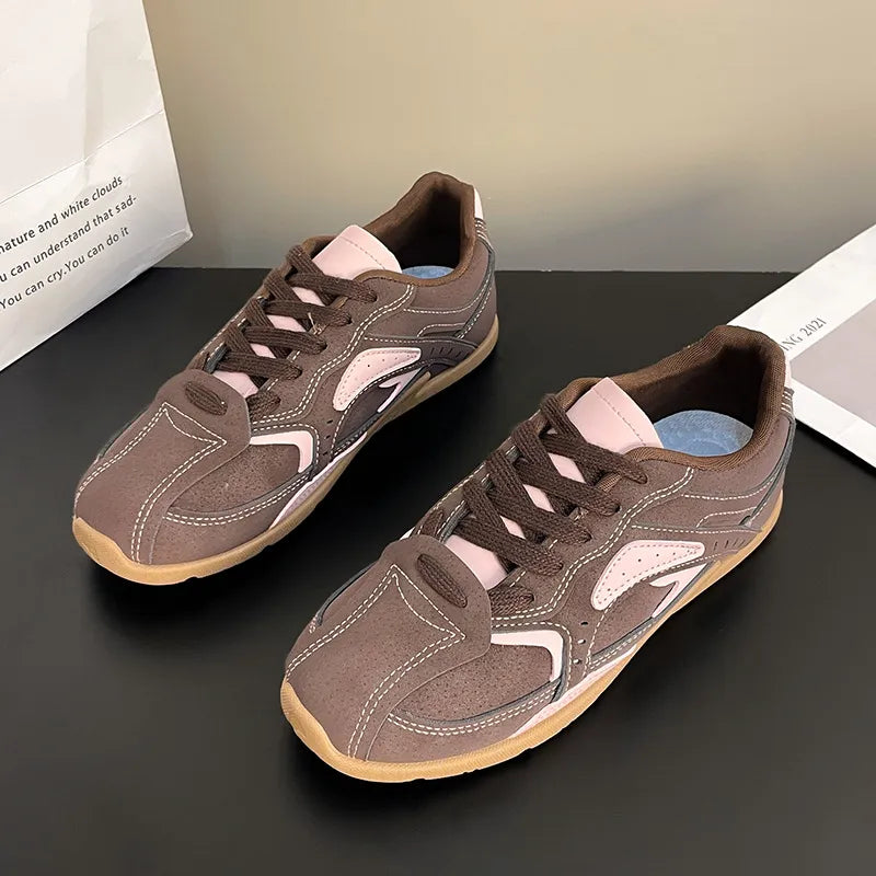 Pair of mocha pink retro lace up sneakers with contrast panels on a dark surface