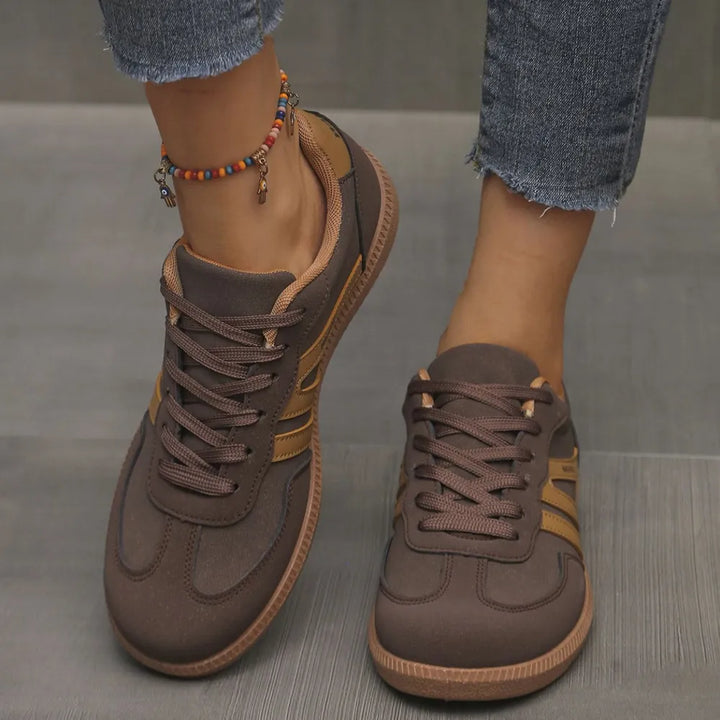 Dark brown retro low top sneakers with tan stripes, worn with an anklet