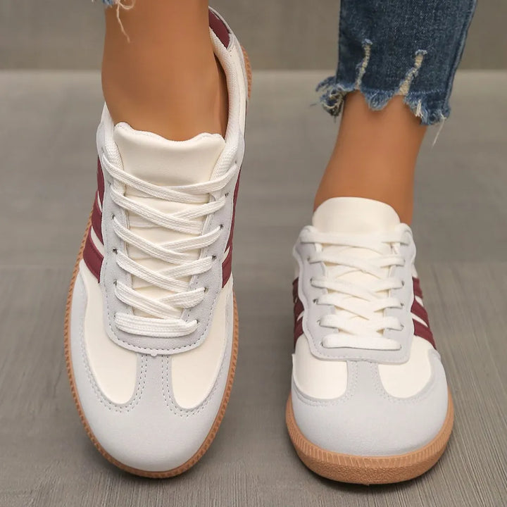 Front view of low top sneakers with white laces and burgundy stripes