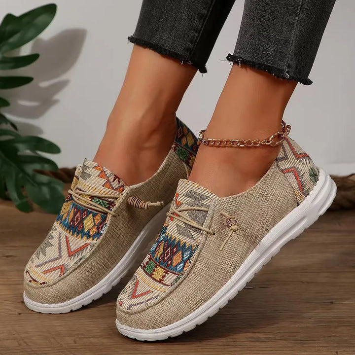 Tan Aztec print slip on sneakers worn with an ankle chain and cuffed jeans