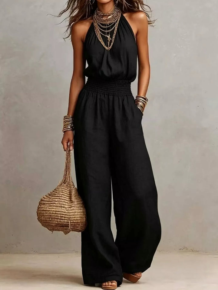 Black halter neck summer jumpsuit with wide leg and a woven bag