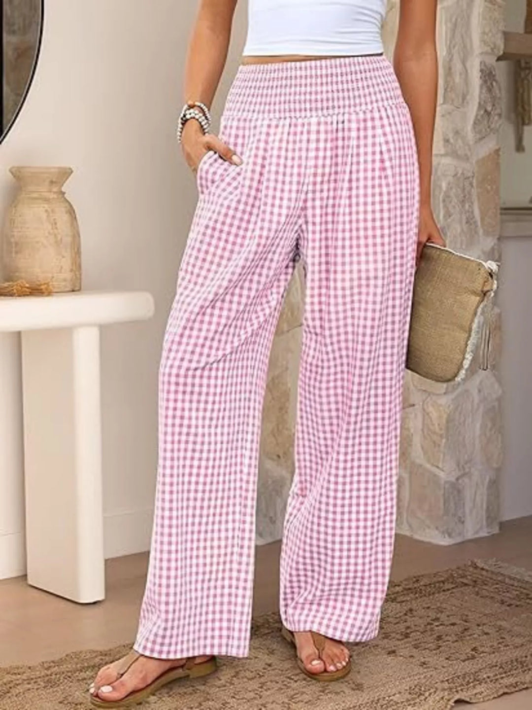 Pink gingham wide leg pants with smocked high waist, front view with straw clutch