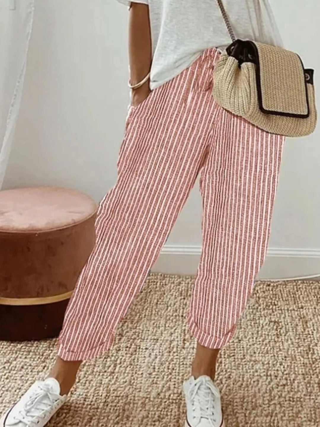 Coral striped cropped pants worn with a white tee and straw crossbody bag