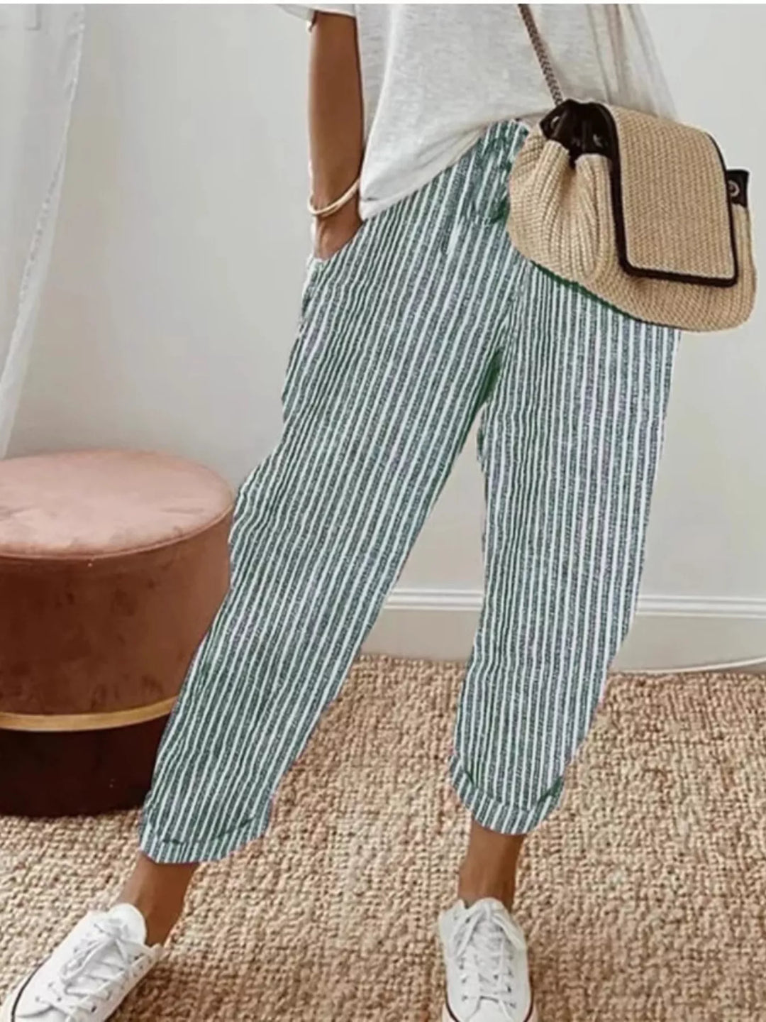 Green striped cropped summer pants worn with white sneakers and a woven bag