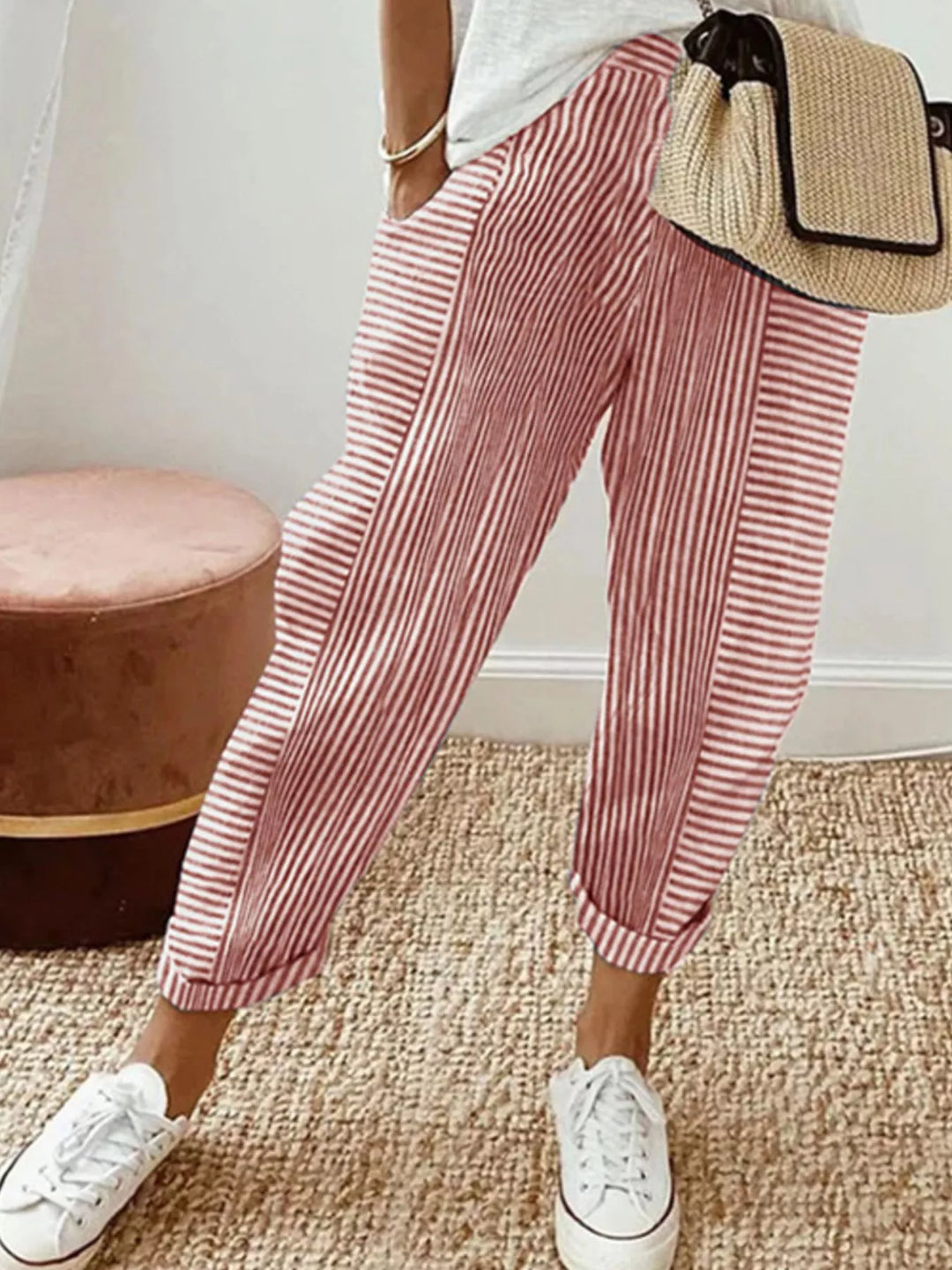 Coral striped tapered pants with cuffed hem, worn with white sneakers and a straw bag