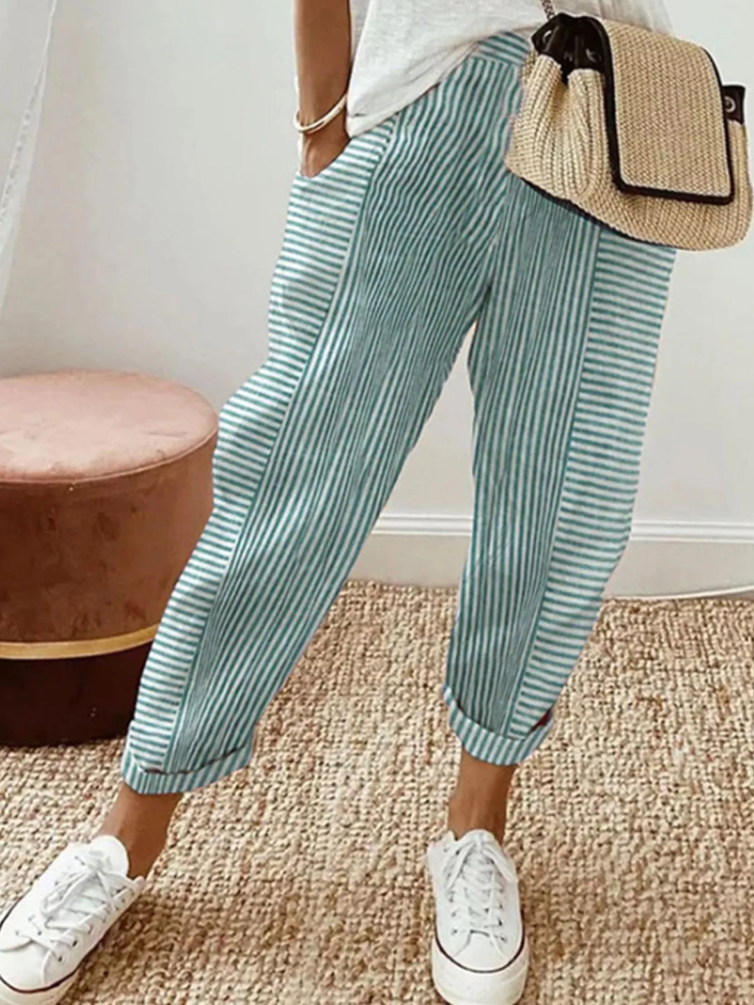 Mint striped tapered pants with cuffed hem and a woven handbag