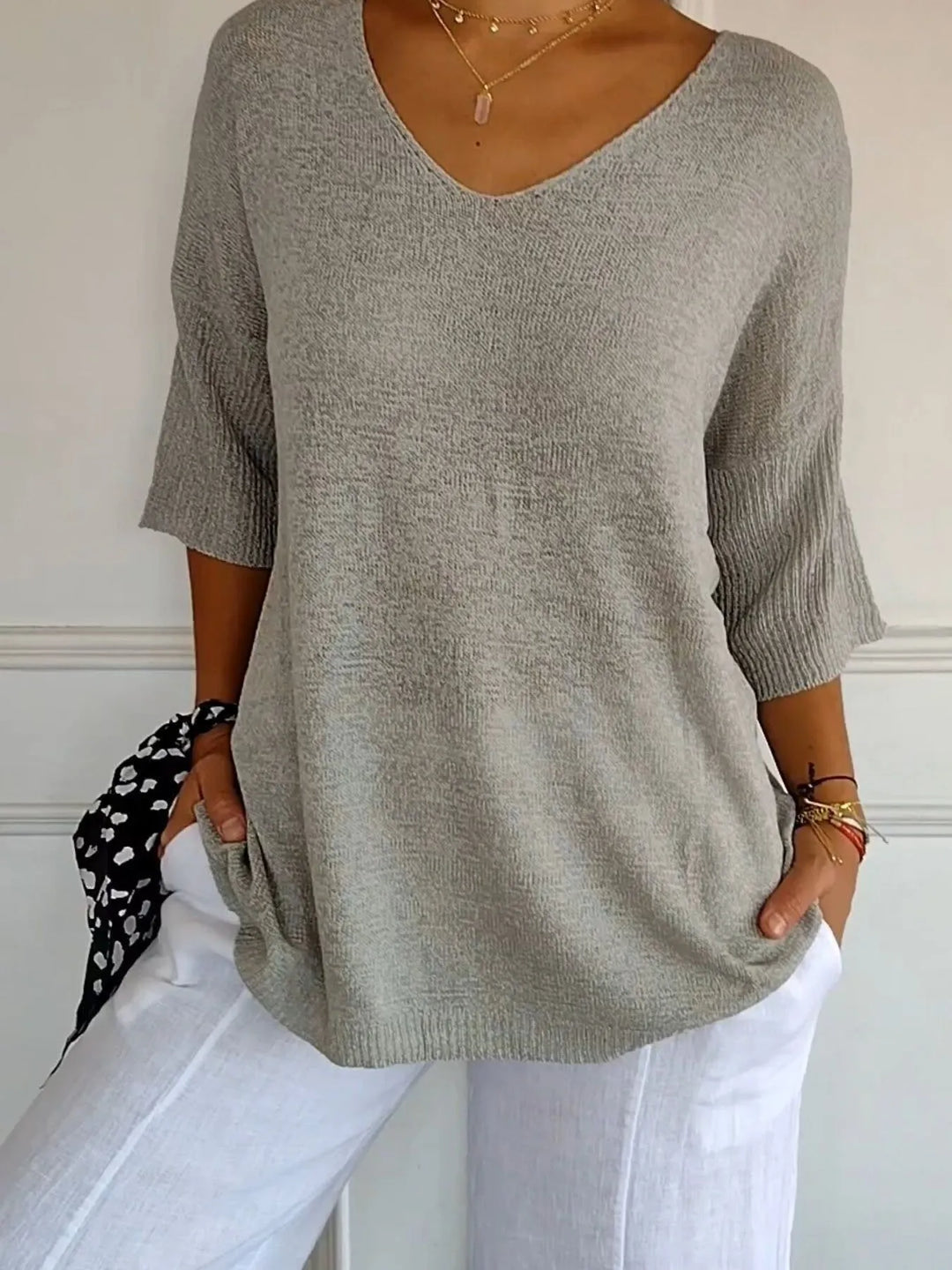 Gray lightweight V neck sweater with 3/4 sleeves and white pants