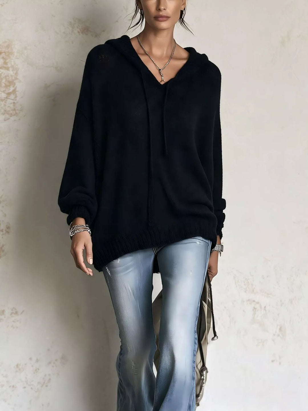 Black hooded knit sweater styled with light wash flared jeans