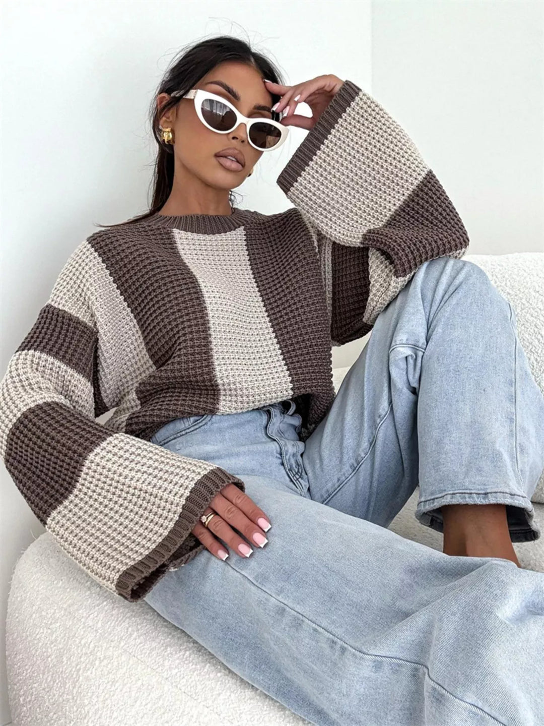 Beige brown waffle knit stripe sweater, seated pose with hand at the sunglasses