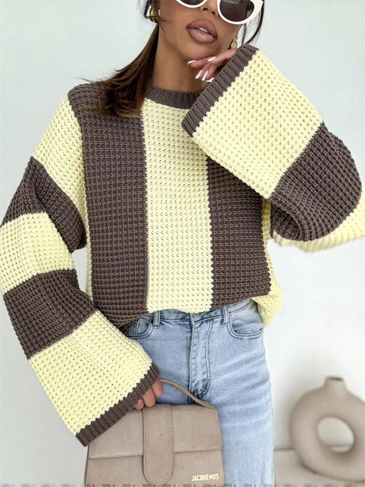 Oversized yellow brown striped sweater with flared sleeves, hand holding a taupe bag