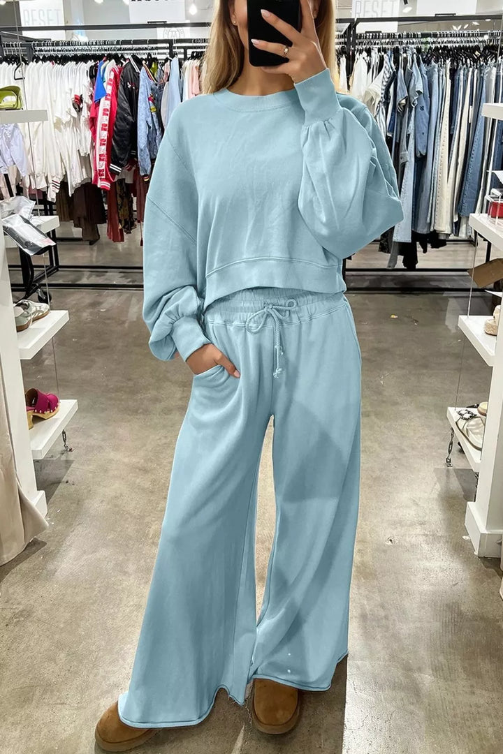 Pastel blue cropped pullover and wide leg pants worn with boots in a boutique
