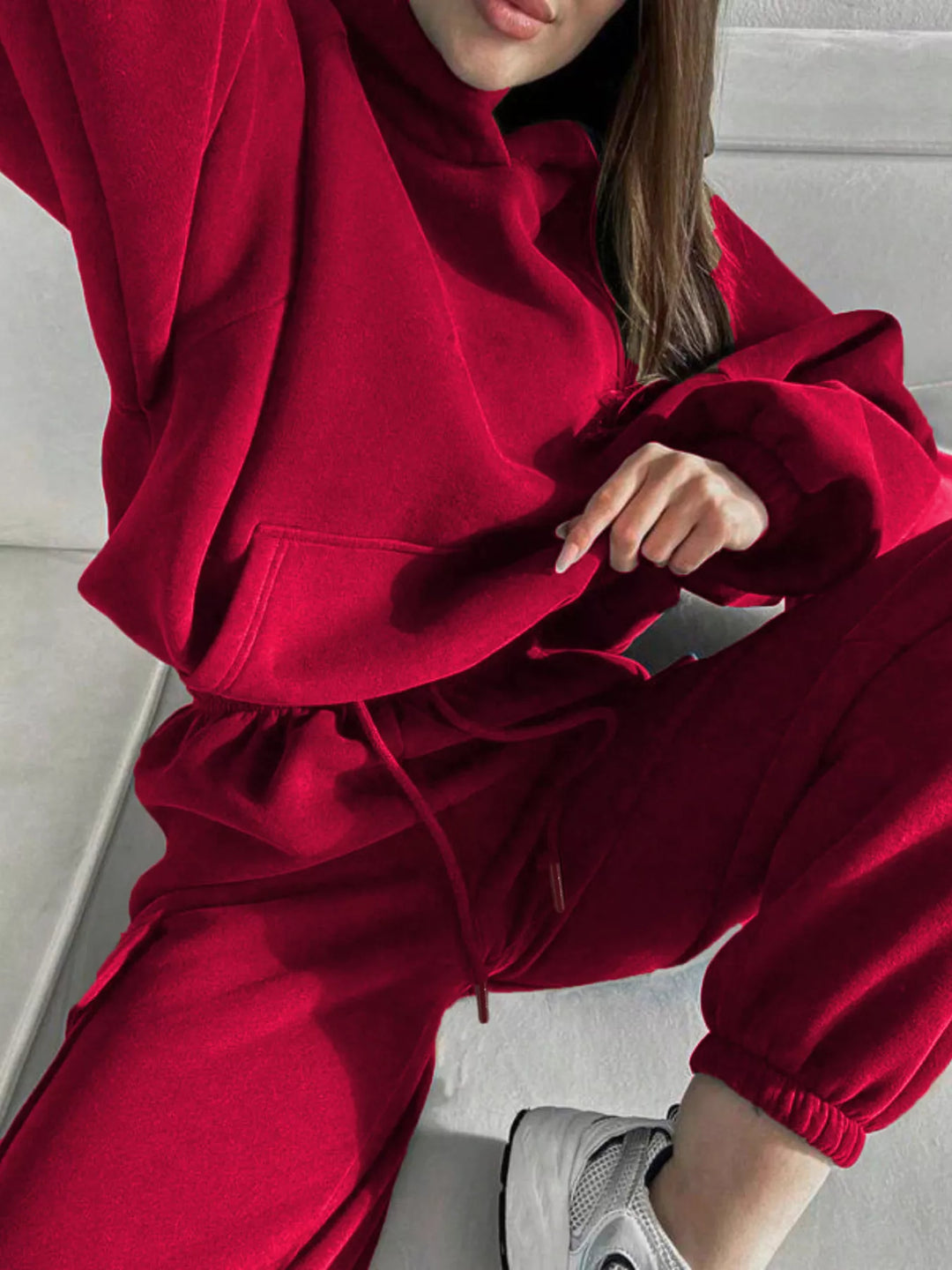 Red hoodie and cargo jogger set in a crouching pose with sneakers
