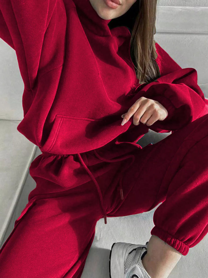 Red hoodie and cargo jogger set in a crouching pose with sneakers