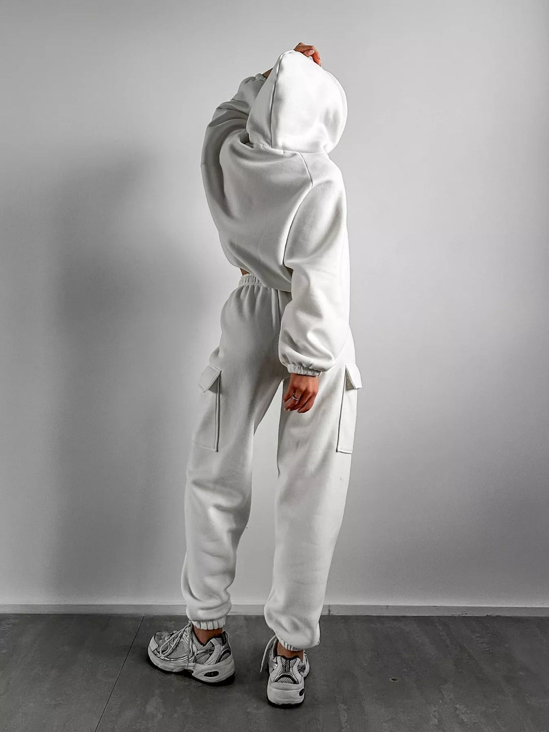 White sweatsuit back view with hood and cargo pocket, paired with sneakers