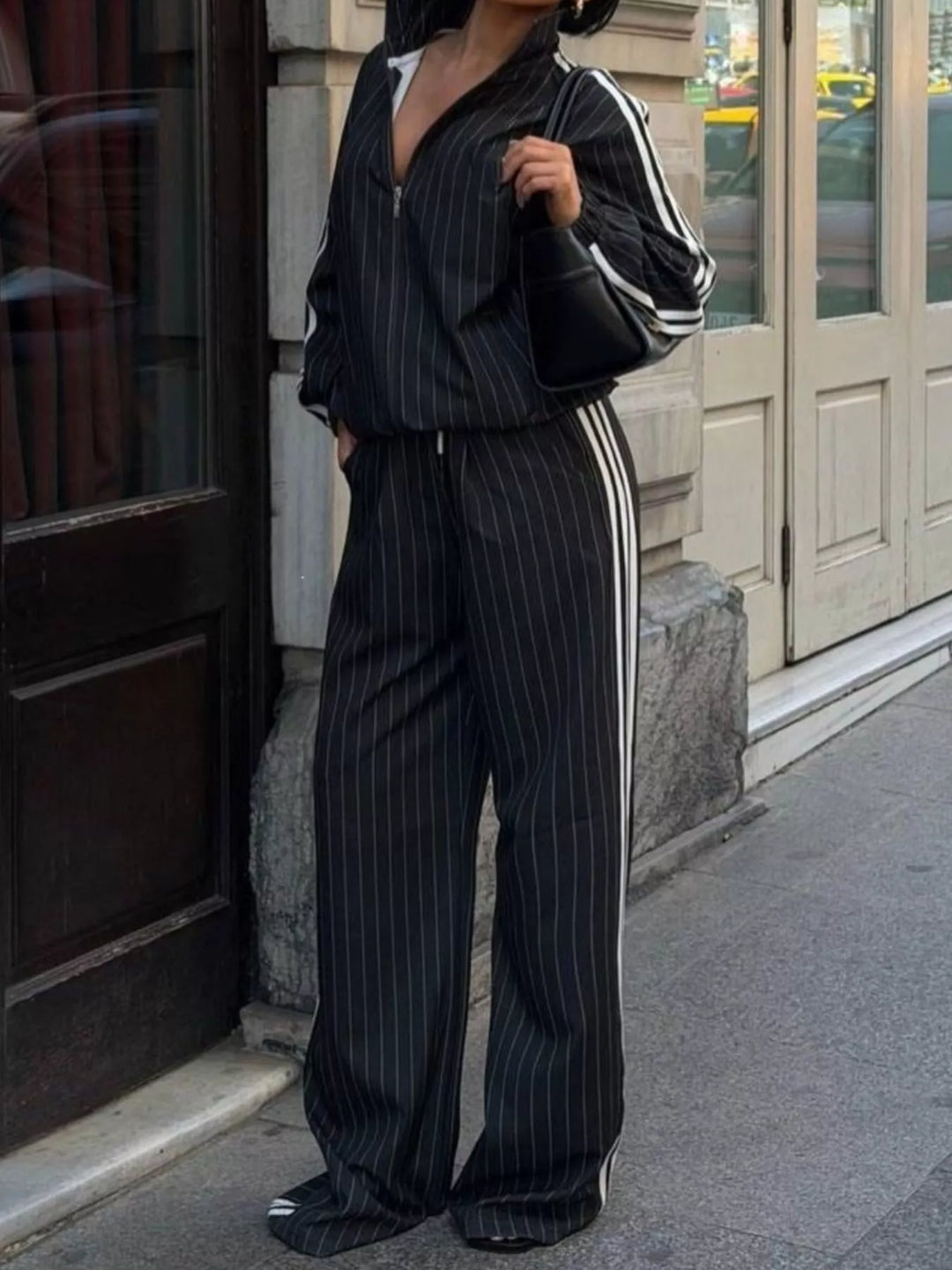 Women's black pinstripe tracksuit set with zip jacket and wide leg pants, full length