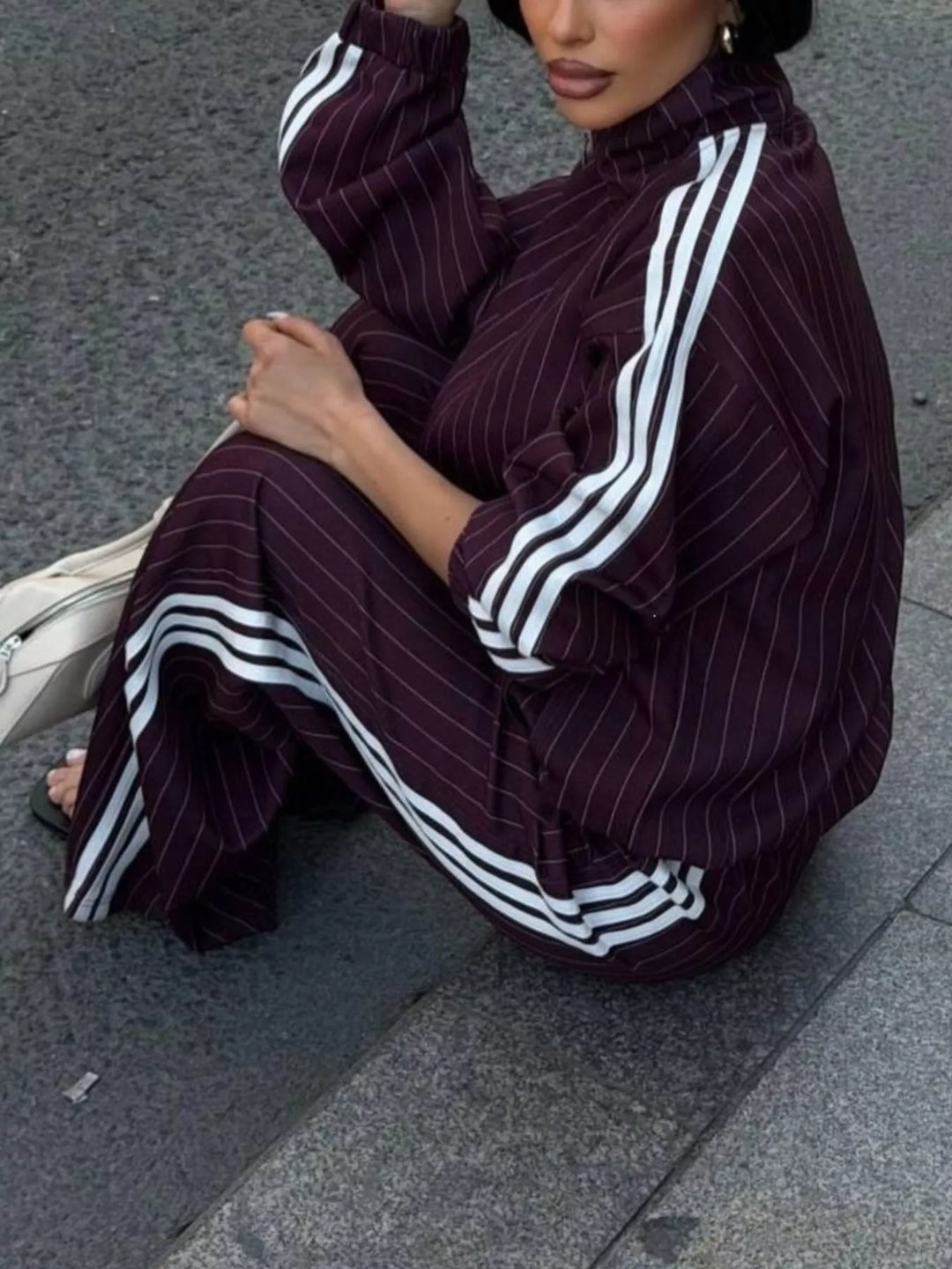Burgundy pinstripe tracksuit set worn while crouching on the pavement