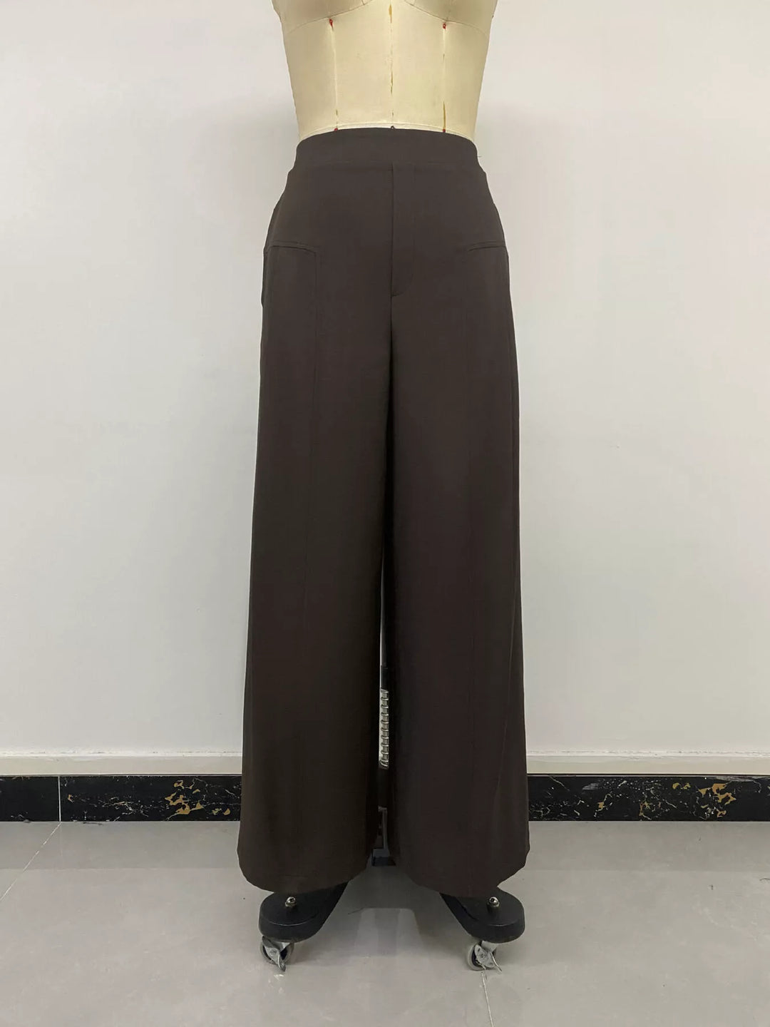Back view of the coffee brown high waisted trousers on a mannequin
