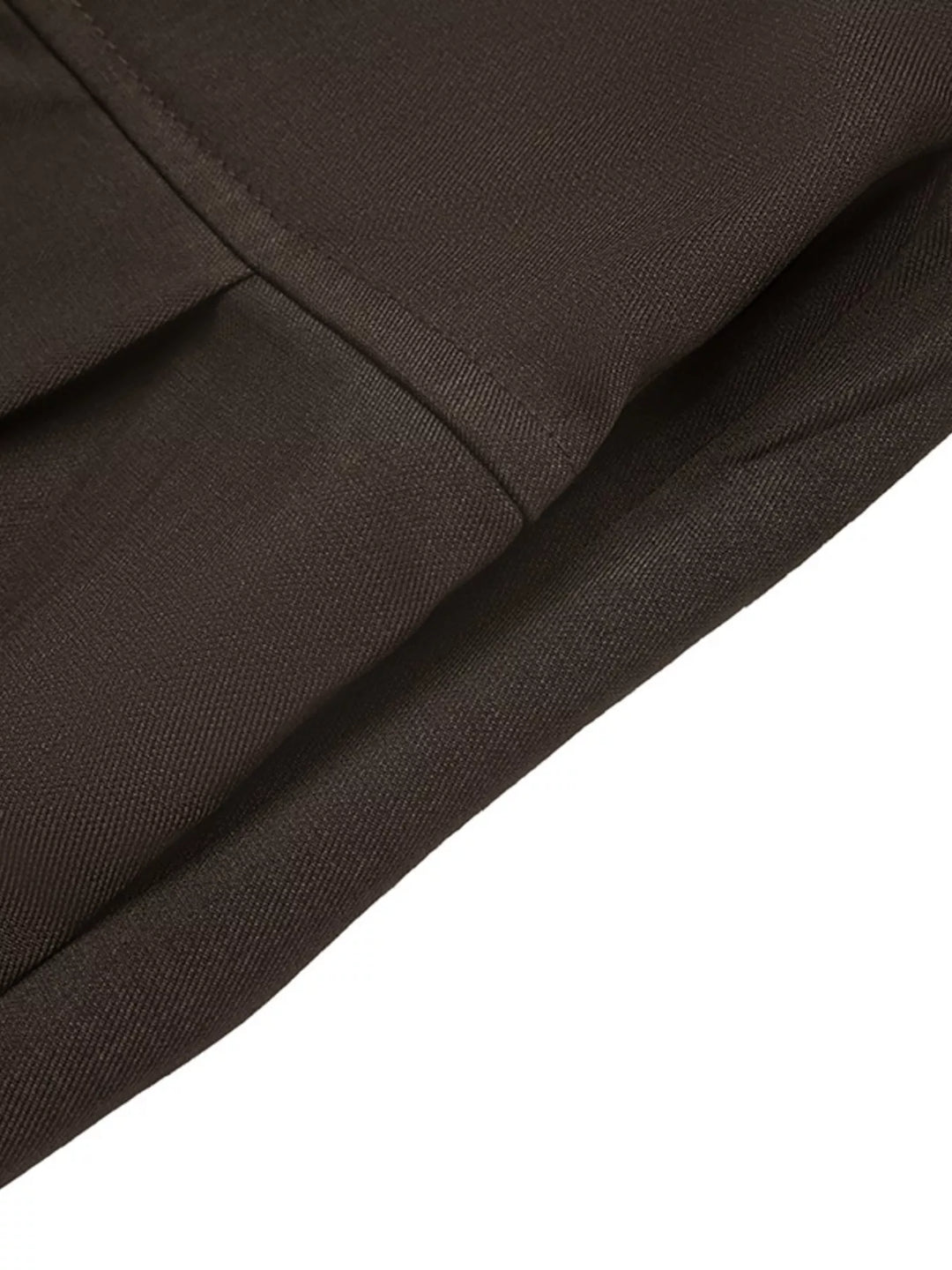 Detail of the pleat seam on the coffee brown trousers, laid flat