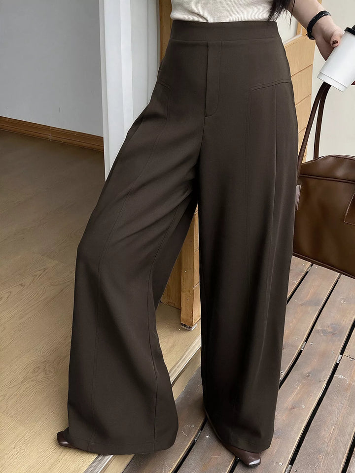 Full-length view of the coffee brown wide leg trousers standing near a doorway