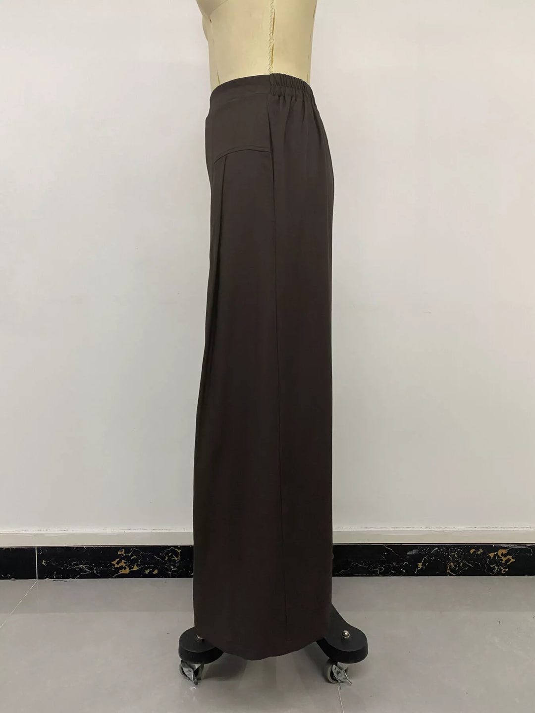 Side view of the coffee brown wide leg trousers on a mannequin