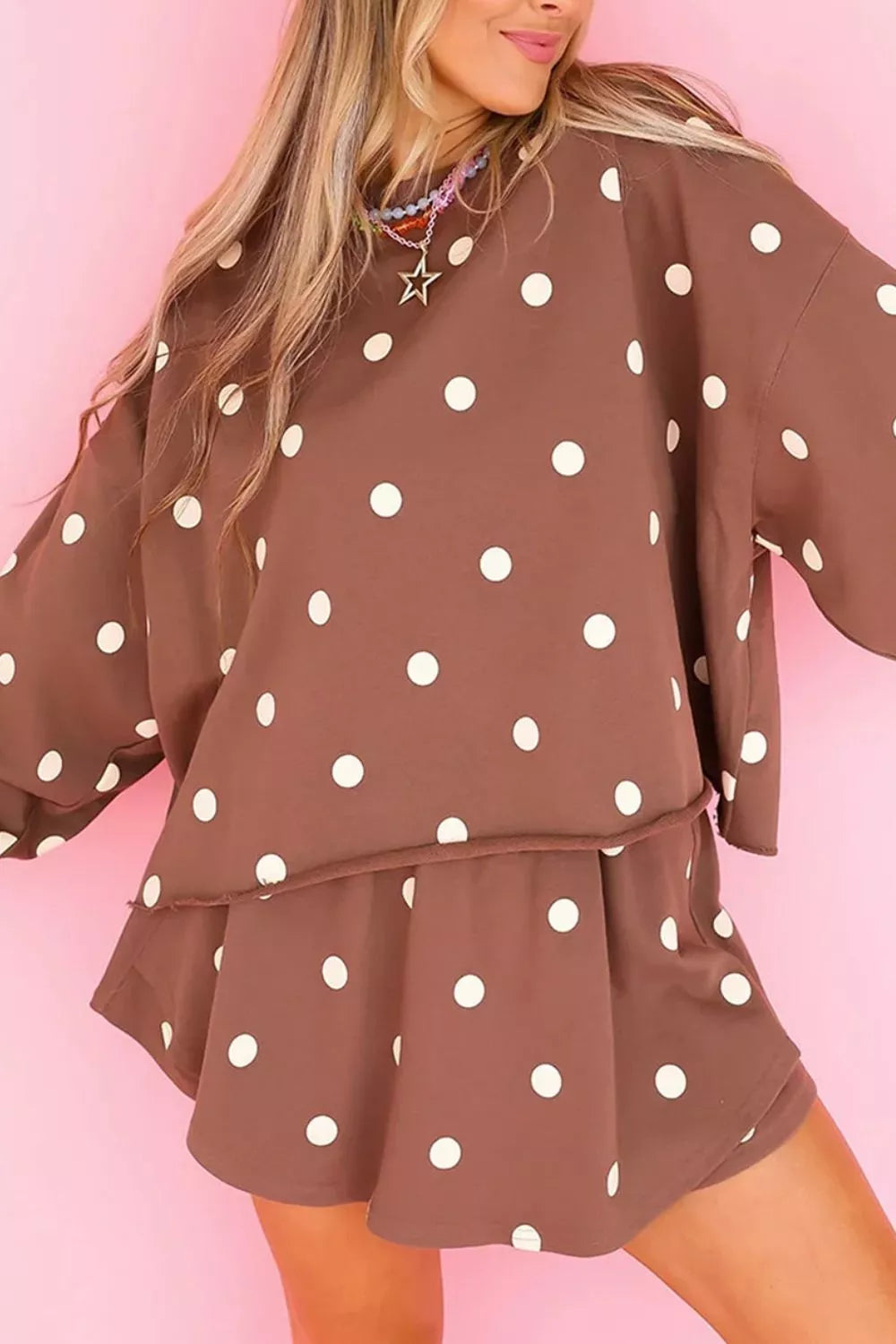 Brown polka dot sweatshirt and shorts set against a pink backdrop