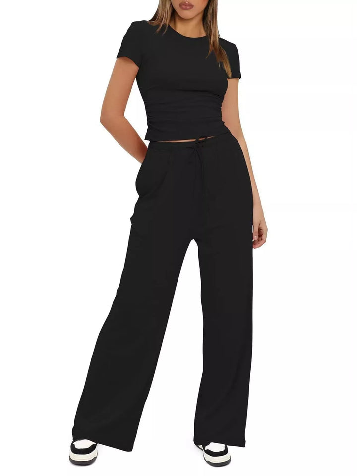 Black ruched crop top and wide leg pants set, standing with a hand on the hip