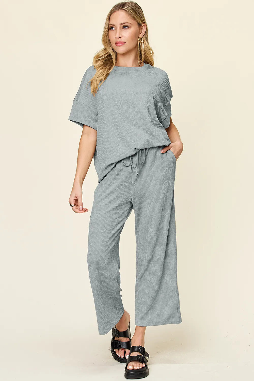 Dusty blue short sleeve top and cropped pants, hands in pockets