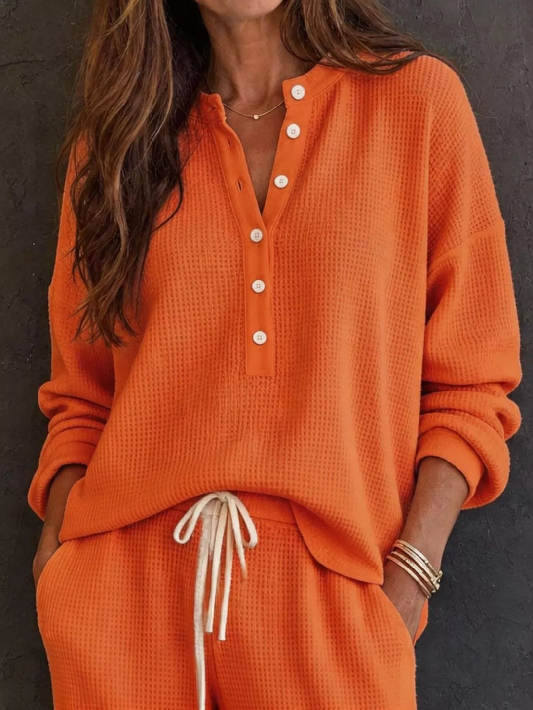 Orange waffle knit henley top with button placket and drawstring pants, close-up