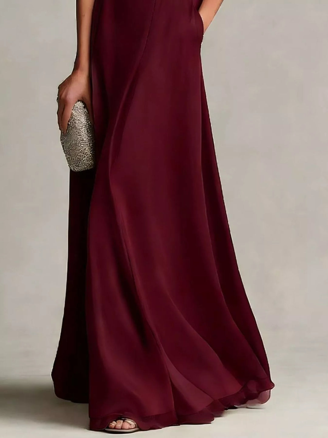 Close-up of the flowing burgundy satin look maxi skirt hem and clutch