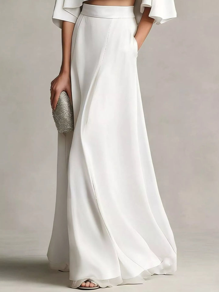 Lower view of the white satin look maxi skirt with a hand in the pocket