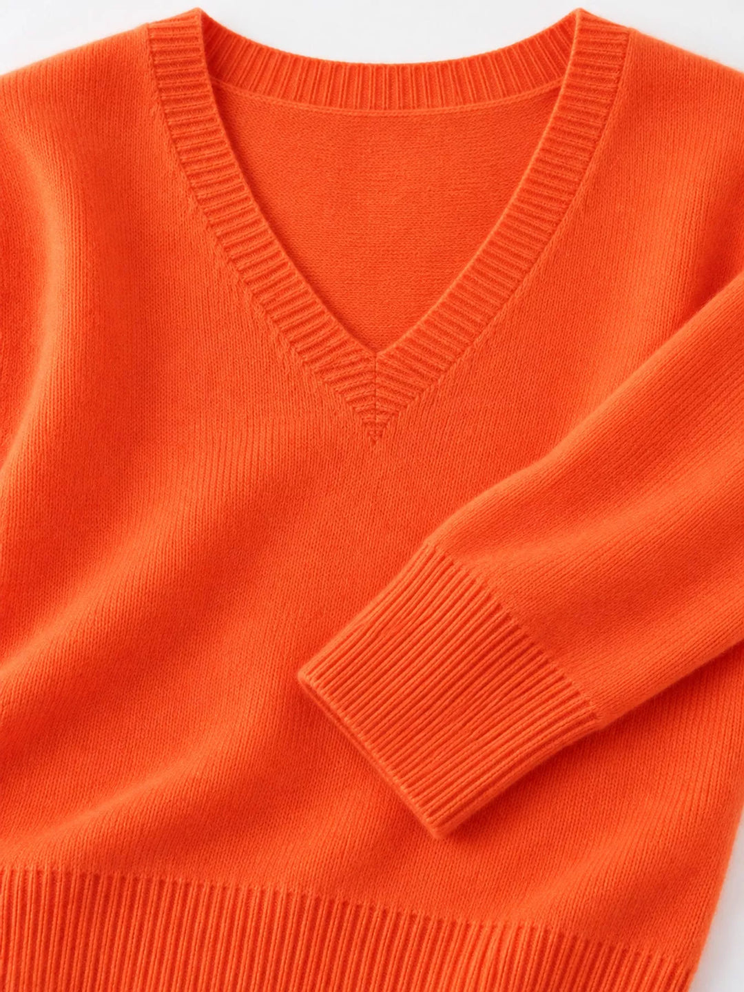 Close-up details of the vibrant orange sweater neckline, ribbed cuff and hem