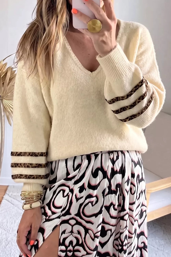 Cream v neck sweater with dark cuff stripes worn over an animal print skirt