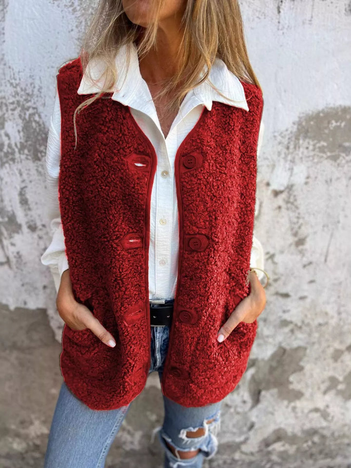 Red fluffy button front vest layered over a white shirt with jeans