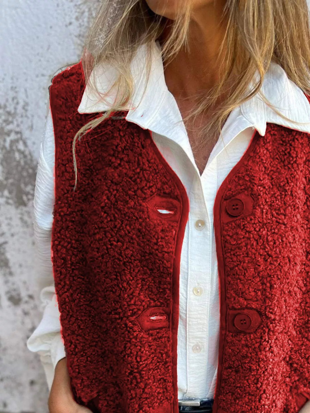 Red button front vest styled open with a white collared shirt underneath
