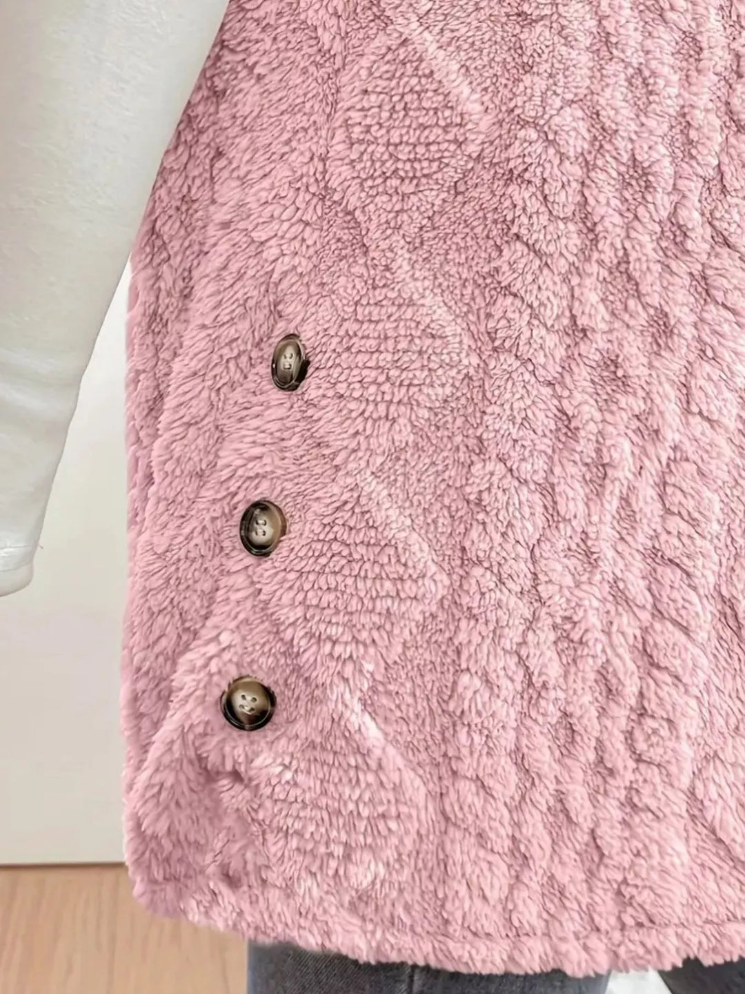 Close-up of the blush pink cable knit texture and side buttons
