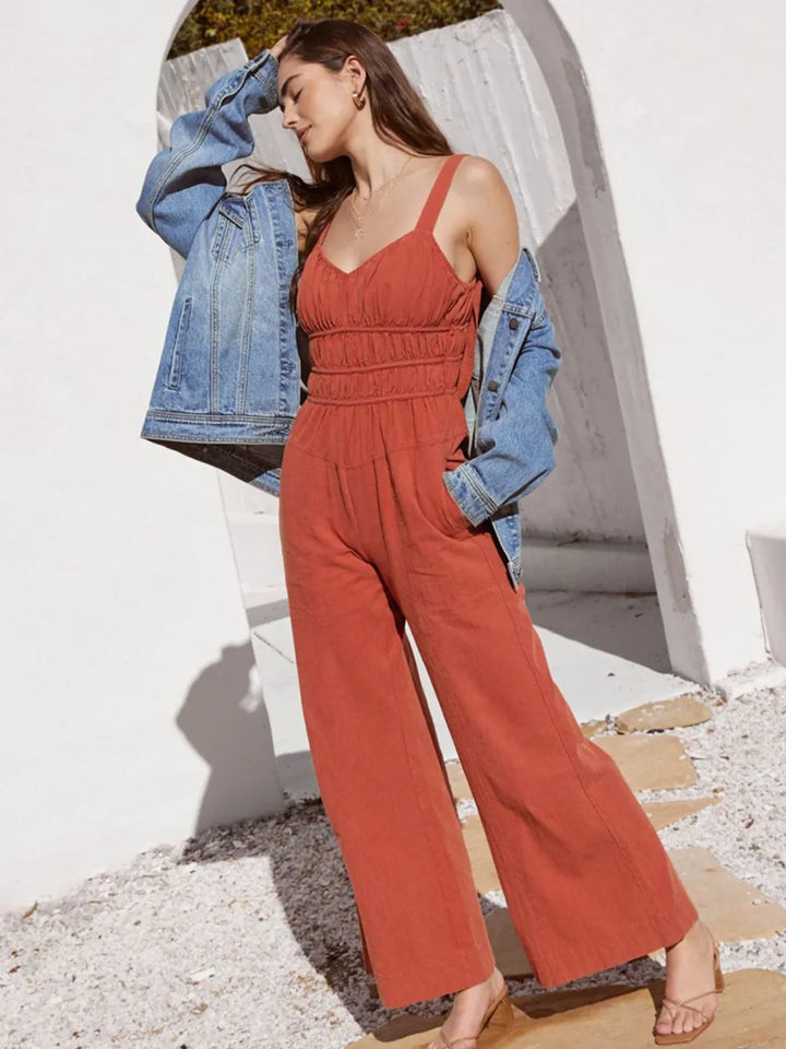 Rust wide leg jumpsuit styled with a denim jacket over the shoulders