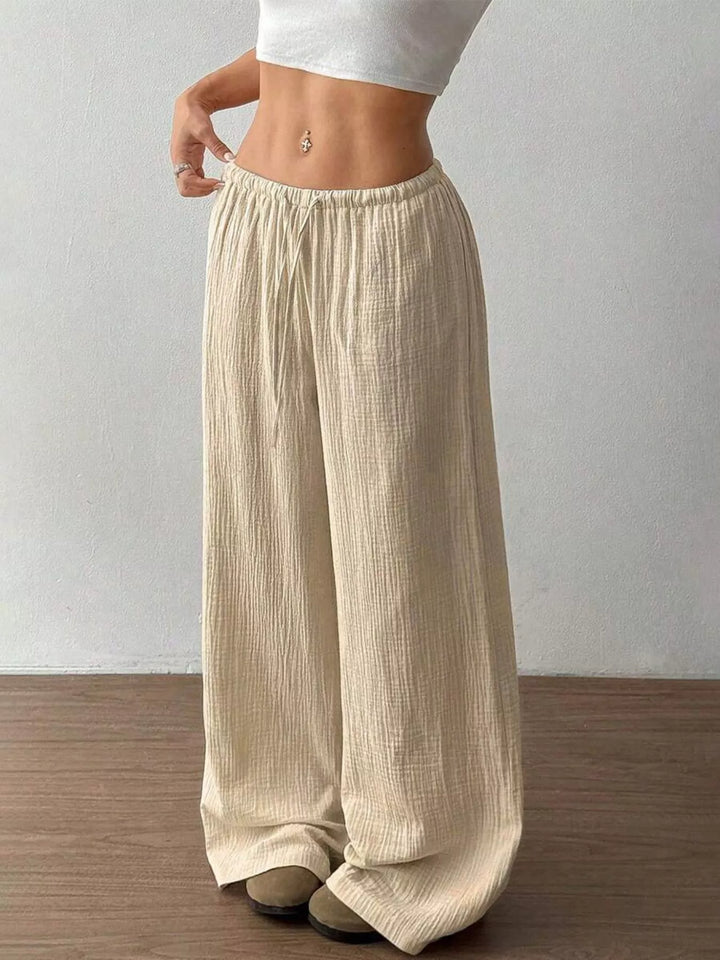Full length beige wide leg pants with a loose hem over the shoes