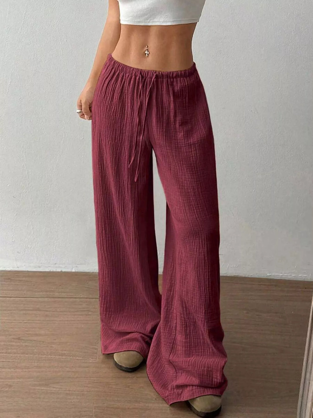 Burgundy crinkled wide leg pants worn low on the waist, front angle