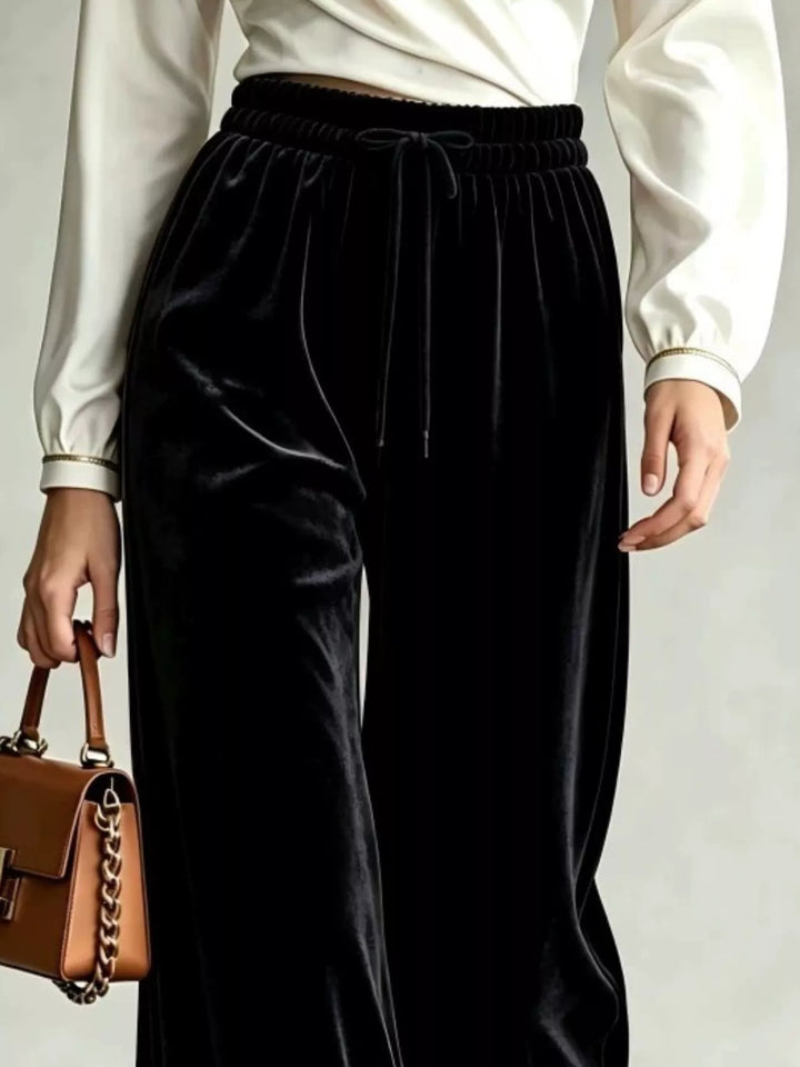 Close-up of the black wide leg pants with tied drawstring and flowing legs