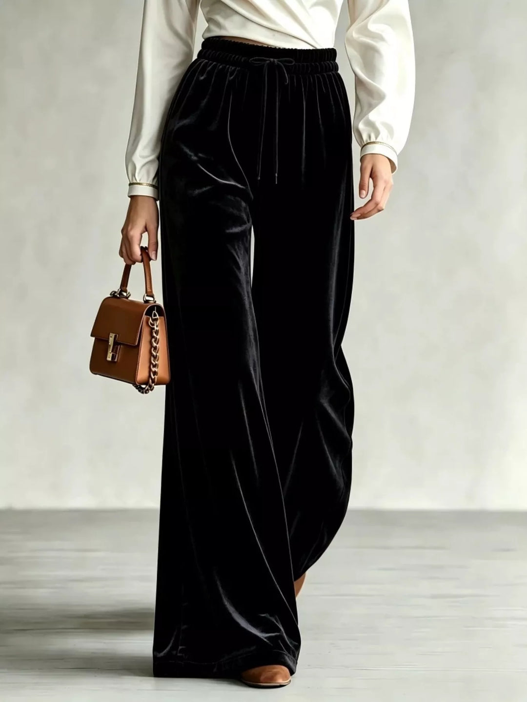 Black velvet-look drawstring wide leg pants with cream blouse and brown bag
